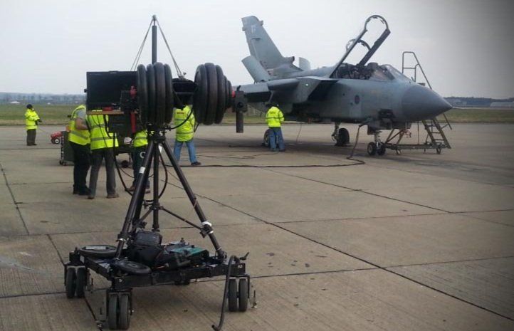 Camera crane rig on a runway beside a fighter jet