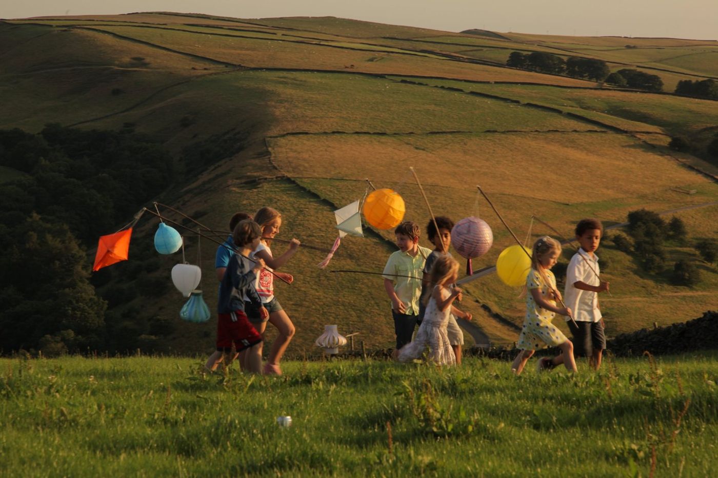 Children running with balloons across a hillside during a shoot
